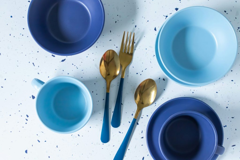 a table topped with blue dishes and gold utensils